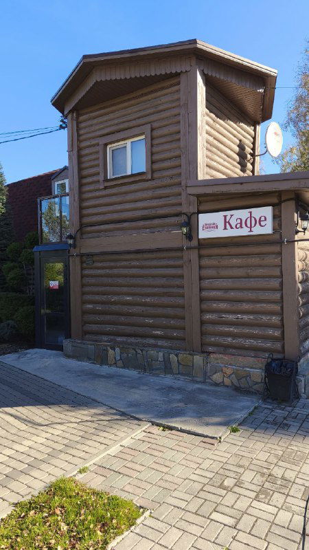 Деревянное здание кафе на территории базы отдыха с вывеской «Кафе», мощёная дорожка и аккуратная отмостка у фасада.