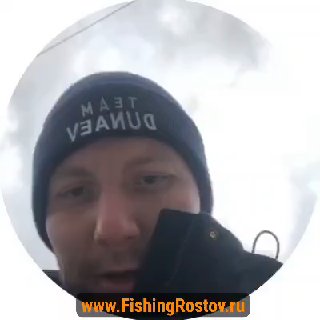 Селфи-кадр рыбака в тёплой шапке с надписью, на заднем плане небо и берег реки; круговая рамка кадра, без указания личности.