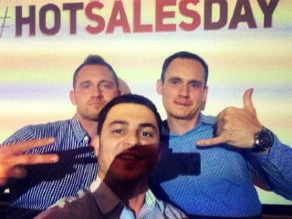 Групповое фото с участниками мероприятия: трое мужчин улыбаются и жестами подчеркивают хорошую атмосферу, на заднем плане брендовый фон HOTSALESDAY.
