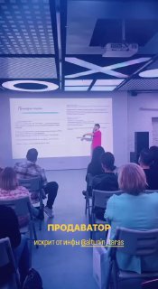 Скрин с видео доклада: спикер на сцене показывает слайд, перед ним аудитория, на экране и внизу подпись с именем докладчика и темой.