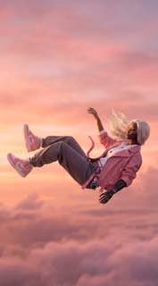 Кадр: человек в горизонтальном положении падает в небе на фоне розового заката; размытый фон и тёплая цветокоррекция.