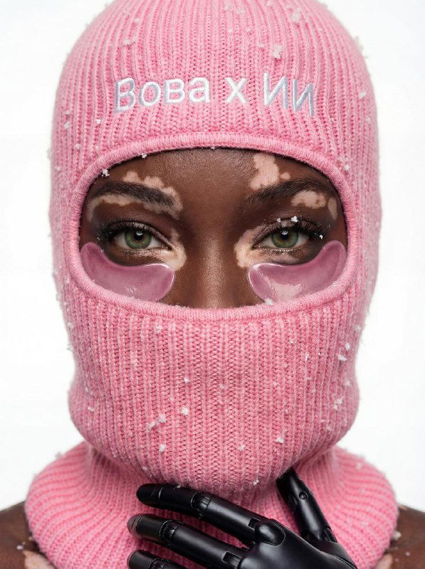 Крупный план лица в розовой балаклаве с вырезом, розовыми патчами под глазами, снежинками и вышивкой «Вова × ИИ» на лбу.