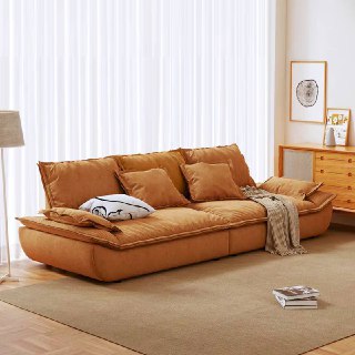 Коричневый кожаный диван Галеон в светлой комнате с занавесками и деревянной тумбой, ракурс показывает боковую часть и подушки.