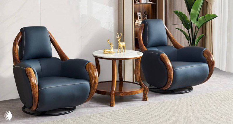 Два тёмно-синих кресла с массивными деревянными подлокотниками и небольшим круглым столиком между ними, мебель с выразительными деревянными рамами.