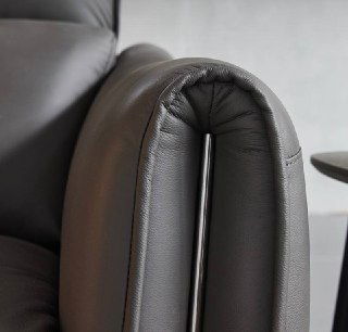 Крупный план изогнутой части подлокотника дивана Cowhide, акцент на мягкой набивке и кожаном покрытии.