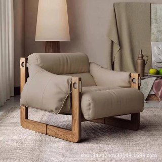 Кресло в бежевой обивке на ясеневая раме, изображение в интерьерной сцене с лампой и текстилем на заднем плане.