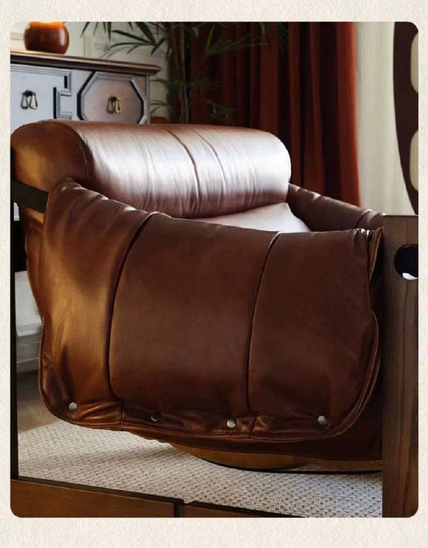 Крупный ракурс кожаного кресла в коричневом тоне на массивной деревянной раме, видно боковые стыки и декоративные крепления.