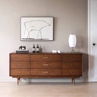 Фасад комода по центру стены: сбалансированные пропорции, минималистичный декор на крышке и художественная картина над предметом мебели.