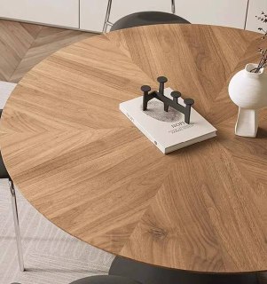 Крупный план деревянной столешницы из ясеня с радиальным рисунком древесины, на столе декоративная книга и минималистичный подсвечник.