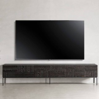 Телевизор над низкой тумбой из ясеня: тумба тёмного тона со скульптурным резным рисунком и минималистичным окружением.