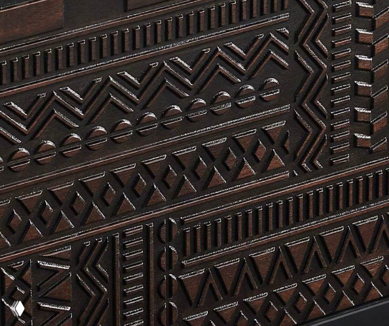 Крупный план резного фасада тумбы из ясеня: орнаментальные геометрические вырезы и тёмная отделка на массивной древесине.