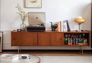 Низкая ТВ-тумба из ясеня на металлических ножках с проигрывателем и декоративными предметами — вид спереди для демонстрации фасада.