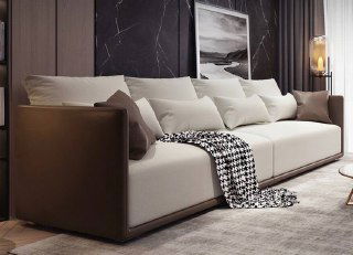 Крупный план дивана с контрастными кожаными боками и мягкими подушками на фоне декоративных картин и тёмных штор.