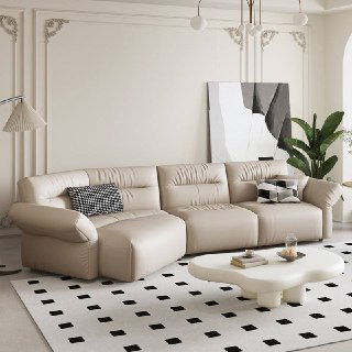 Прямой бежевый кожаный диван в элегантной комнате с белой лепниной и низким кофейным столом, интерьер в нейтральной палитре.