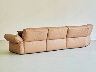 Вид сзади на коричневый кожаный диван — показан профиль, форма спинки и подушек на светлом однотонном фоне студии.