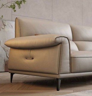 Крупный план подлокотника и шва дивана в бежевой коже, видно фурнитуру и ножку — деталь отделки и качества материалов.