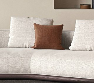 Крупный план коричневой декоративной подушки на светлом диване, контрастная деталь дизайна, подчёркивающая текстуру и цветовую гамму модели.