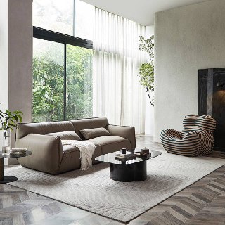 Широкий диван Navola в интерьере с высокими окнами, общий вид на зону отдыха с журнальным столиком и растениями