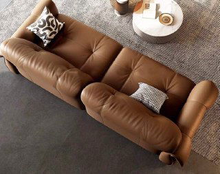 Вид сверху на коричневый кожаный диван: фактура обивки, мягкие подушки и форма сидений — акцент на конструктивных деталях и комфорте.