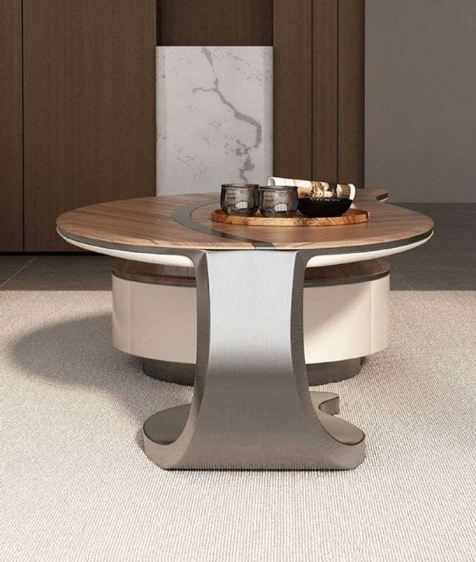 Ракурс круглого журнального столика со стальной ножкой сложной формы и деревянной столешницей, интерьер в тёплых оттенках.