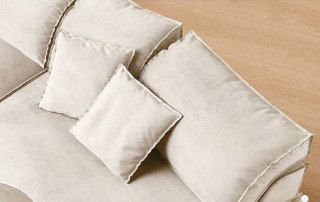 Крупный план подушек и секции дивана: текстура светлой ткани, швы и мягкая набивка, видно качество обивки и фурнитуры