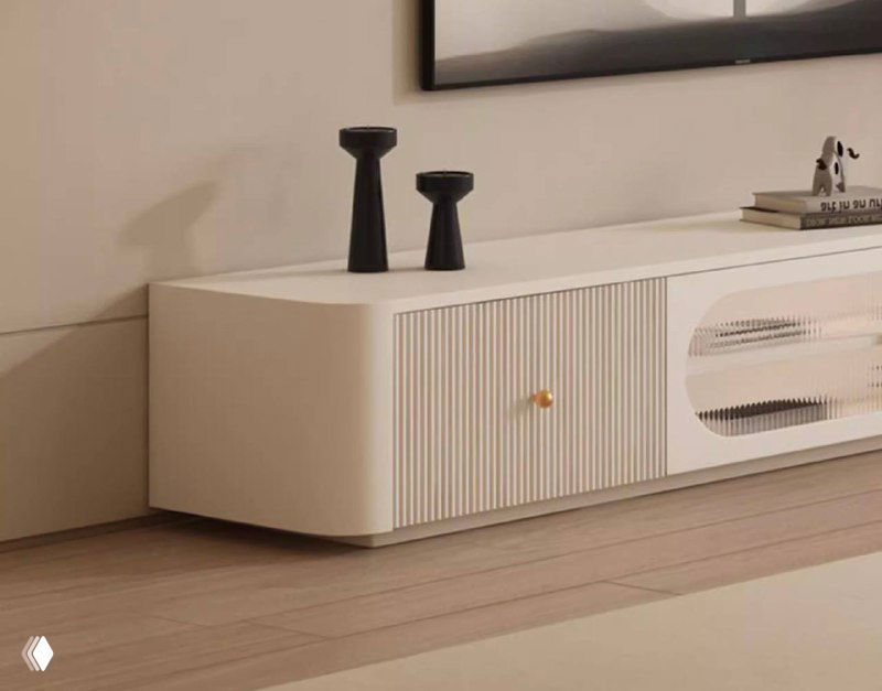 Фрагмент белой тумбы: рельефная вертикальная фактура на фасаде, золотистые ручки и плавные углы в скандинавском стиле интерьера.