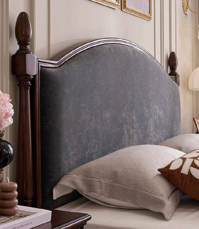 Детальный кадр мягкого изголовья кровати: обивка спокойного серого оттенка на фоне резных деревянных стоек из ясеня.