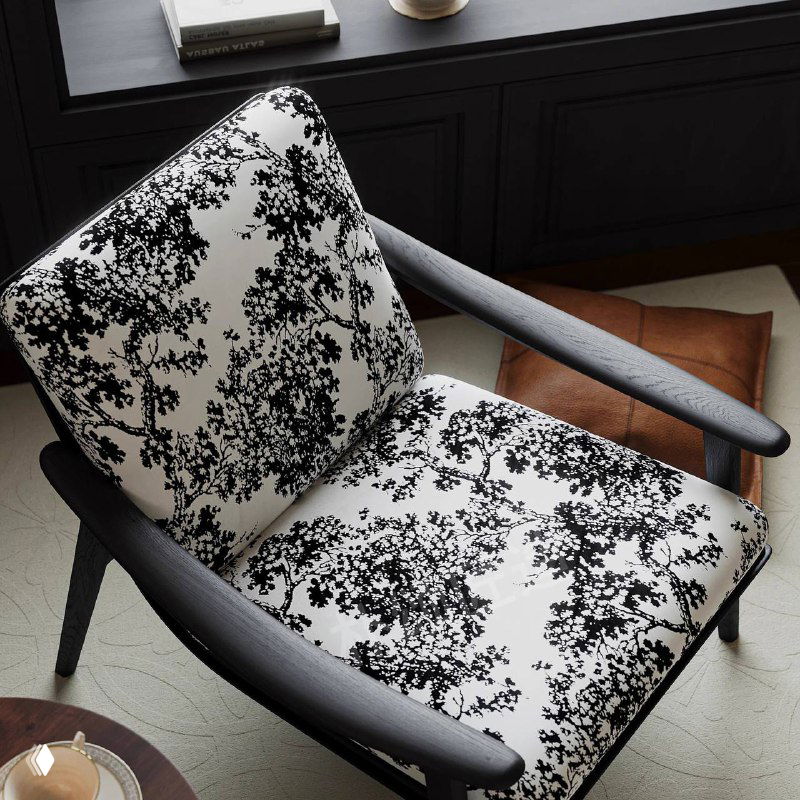 Крупный план кресла из ясеня с черно‑белой текстурированной обивкой; вид на подушку и подлокотник, демонстрация рисунка ткани и деталей каркаса.