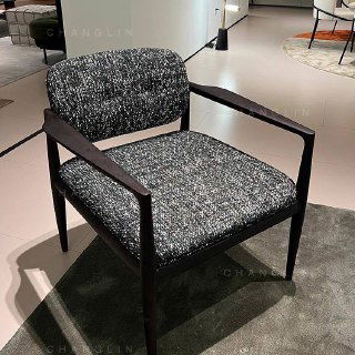 Кресло из ясеня на выставочном подиуме: плотная сидячая часть и широкий спинка в тканевой обивке, на ней видно фактуру материала.