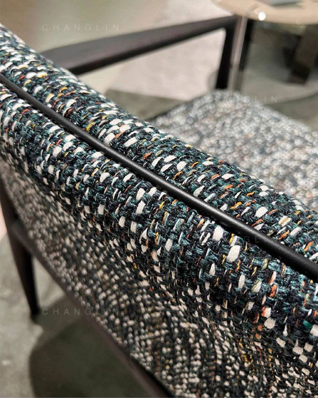 Макро-фото фактуры ткани кресла: комбинация тёмных и светлых нитей, видна плотность переплетения и цветовые вкрапления нитей.