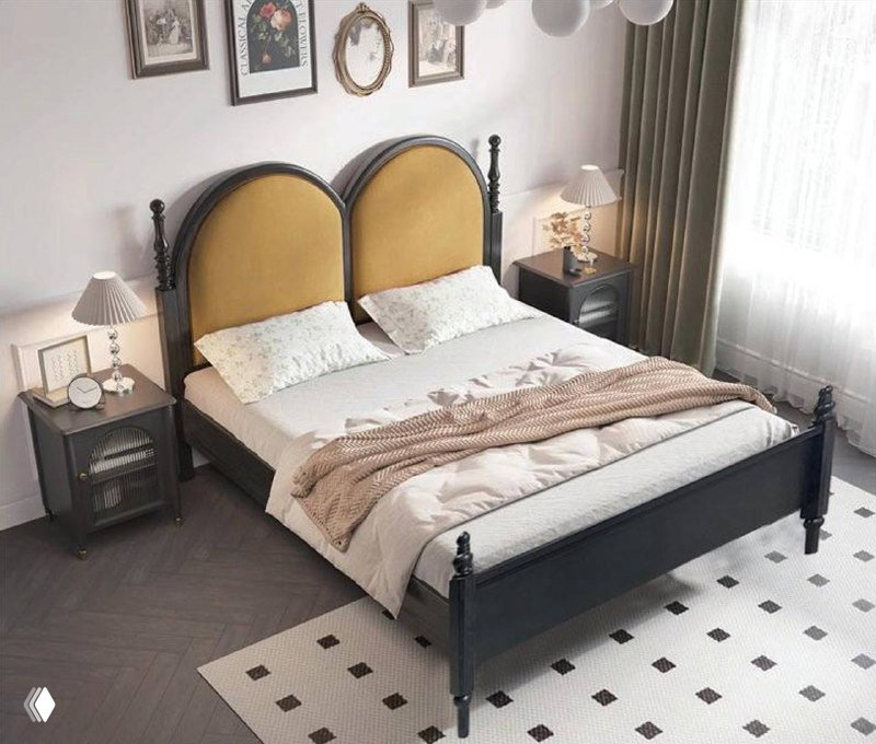 Двуспальная кровать у окна: пара округлых изголовий в горчичном тоне, тёмная рама, постель и ковер — пример стилизованной спальни с естественным светом.