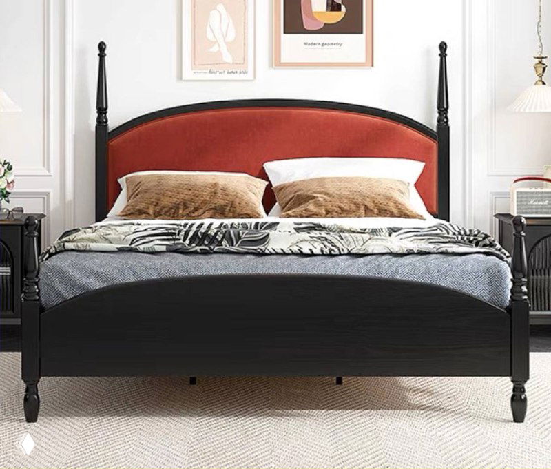 Кровать с высоким изголовьем в тёплом бордовом оттенке, чёрная рама, декоративные подушки и светлый ковёр — интерьер в современном классическом стиле.