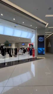 Интерьер торгового уровня с витринами магазинов и просторным белым полом, один из торговых проходов Marina Mall.