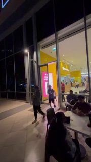 Вечернее пространство у входа с небольшими кафе и посетителями на открытой площадке рядом с набережной Marina Mall.