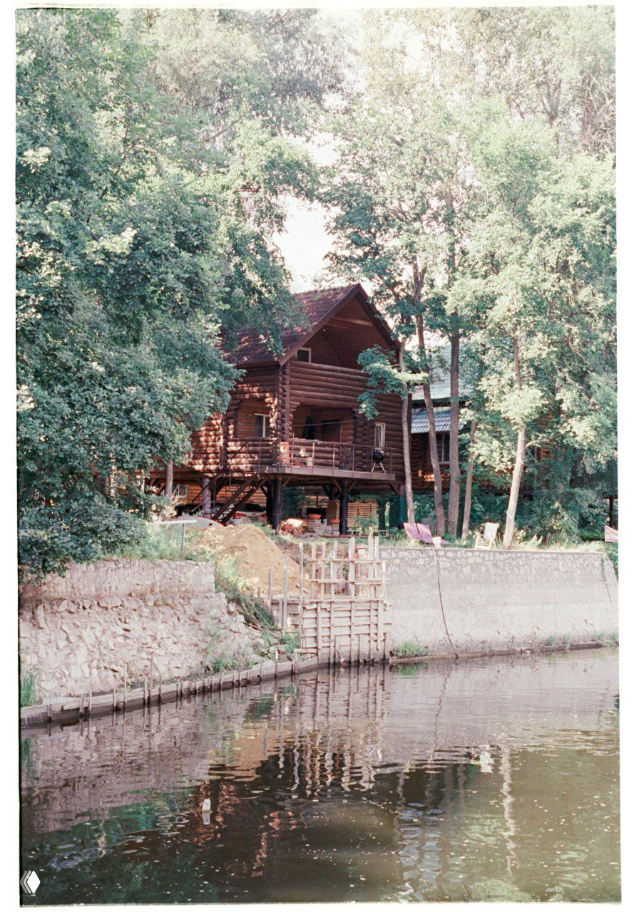 Скан плёнки Kodak Vision3 250D: дом на берегу пруда с отражением в воде, приглушённые пастельные цвета и заметно меньшее зерно, чем у Color Plus.