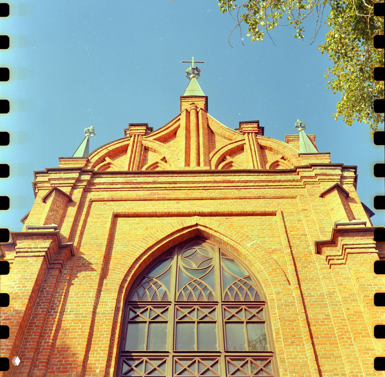 Фасад костёла с аркой и готическим окном, снято снизу вверх; видны края кадра и характерная текстура плёнки; Mamiya C220.