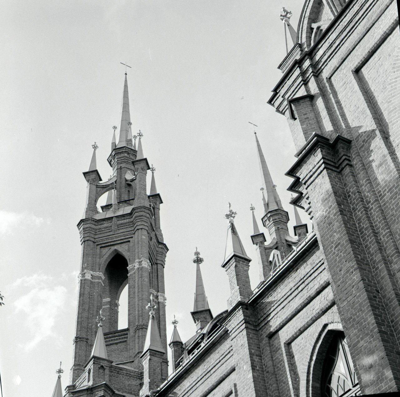 Чёрно‑белый снимок шпилей и крыши костёла: высокий контраст, заметное зерно и тональность проявки на ч/б плёнке; D-76.