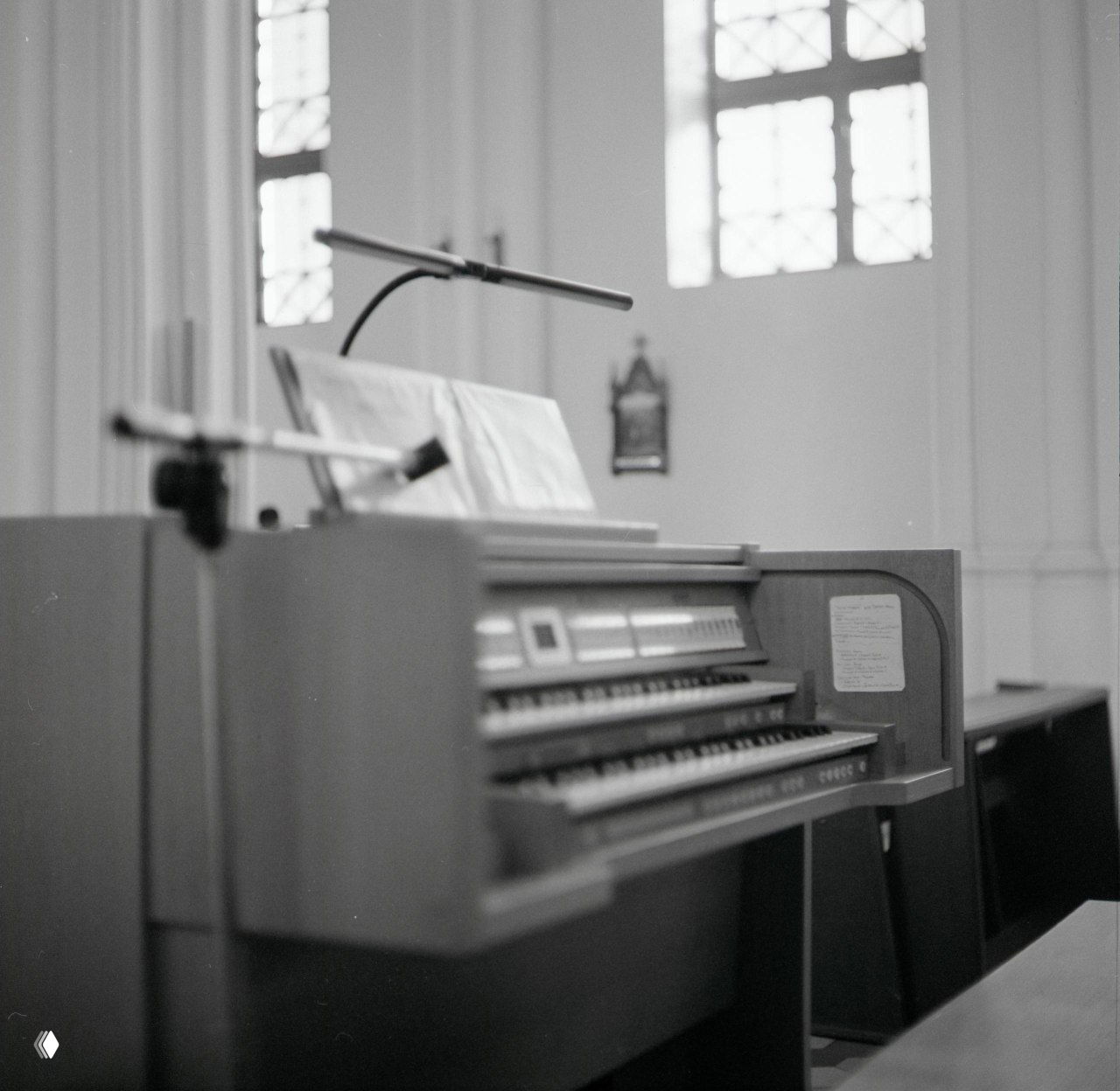 Интерьерный чёрно‑белый кадр: орган в предфокусе, размытый алтарь и окна в глубине; результат проявки ч/б плёнки в D-76.