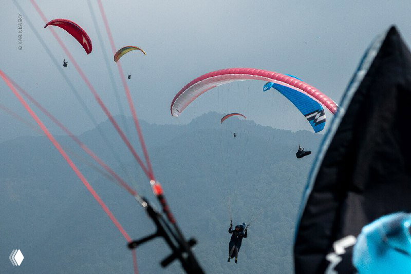 Несколько парапланов в небе на фоне гор и облаков — групповой полёт курса маршрутных и термических полётов в индийских горах.