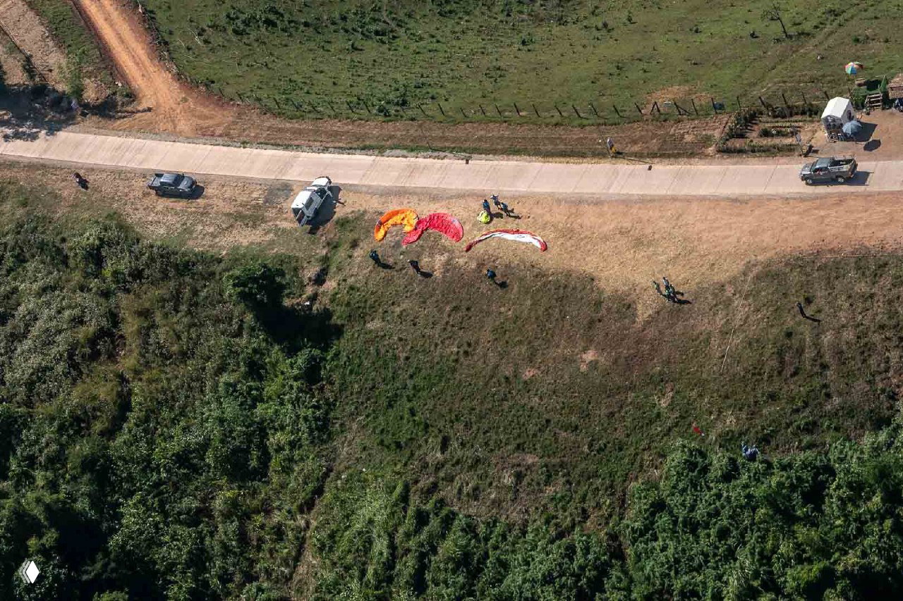 Вид сверху на подготовку экипажа и несколько расстеленных крыльев у дороги: сцена наземной логистики и подготовки перед полётами.