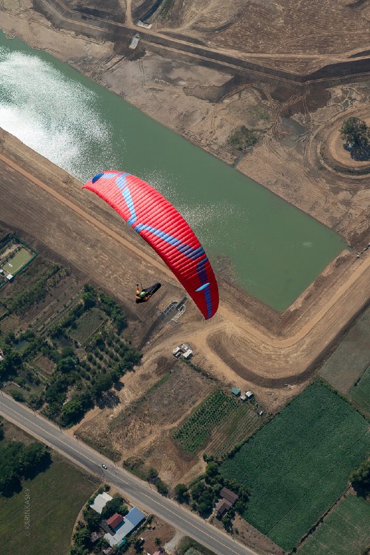 Параплан идёт вдоль искусственного водоёма и сельских полей, вид сверху подчёркивает маршрут и сельский рельеф внизу