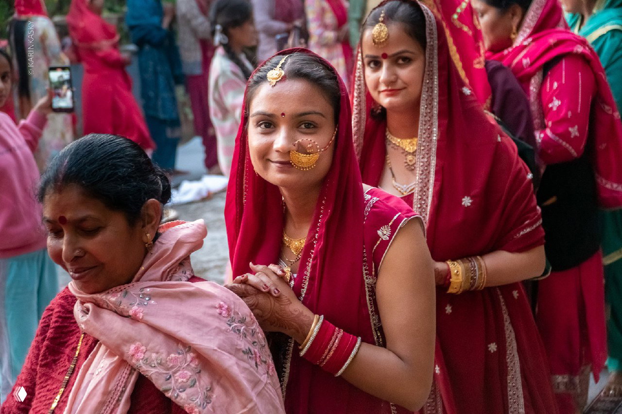 Группа женщин в традиционных ярких одеждах на улице, портретная сцена с тёплым выражением лиц и культурным колоритом