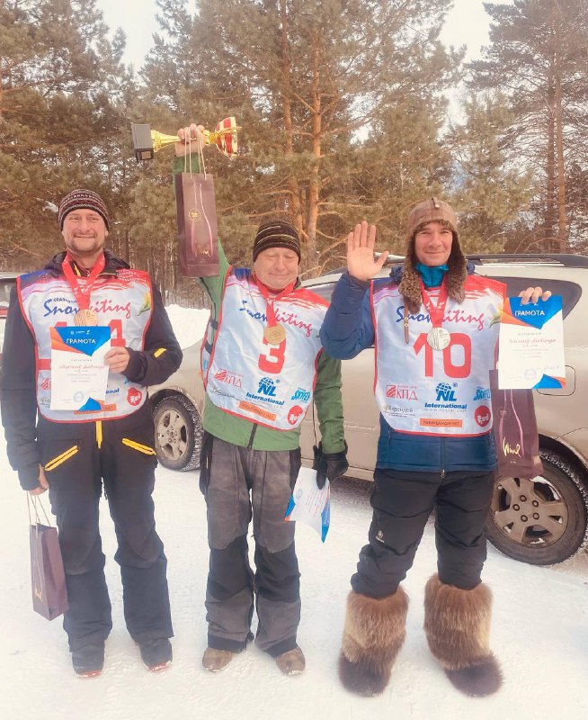 Победители на подиуме с дипломами и подарками: три спортсмена позируют вместе после церемонии награждения Чемпионата Красноярского края.