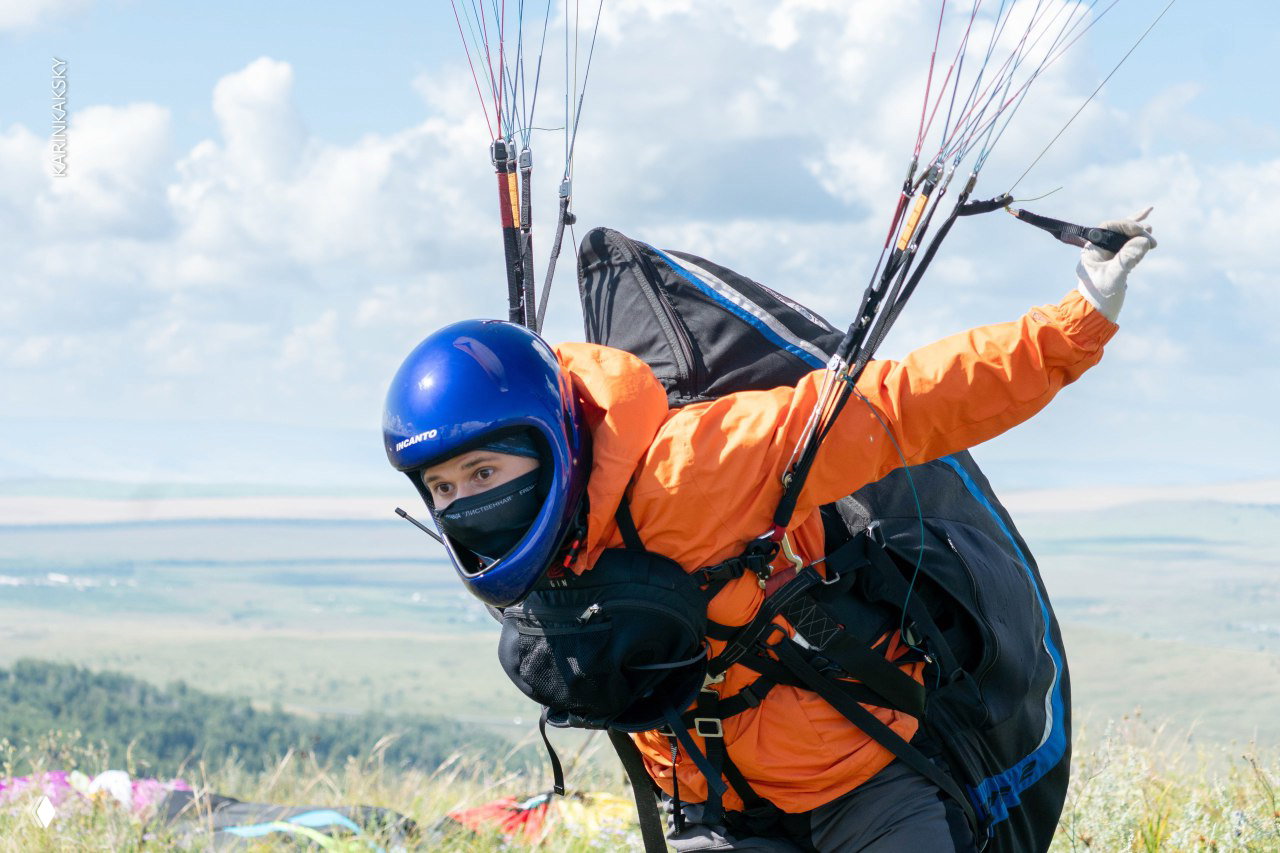 Парапланист в одиночном полёте над облачным небом: силуэт в подвесной системе и просторная голубая атмосфера вокруг.