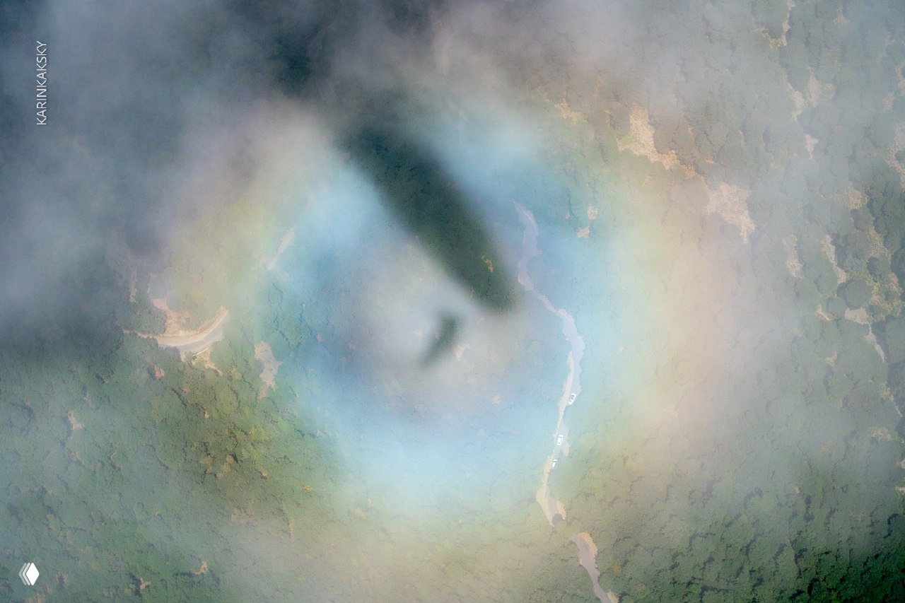 Вид сверху: облачный ореол и тень параплана на фоне индийских предгорий — атмосферный кадр с эффектом радуги в облаках.