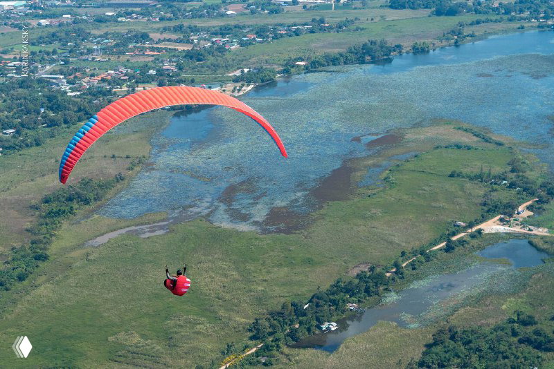 Ярко-красный параплан на фоне болотистых лугов и рек — панорамный вид природы Таиланда из подвесной системы пилота.