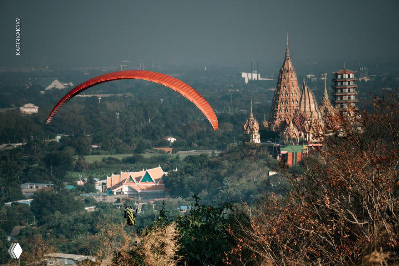 Параплан над холмом с видом на храмовый комплекс и зелёный ландшафт, сочетание полёта и культурного окружения в регионе полётов.