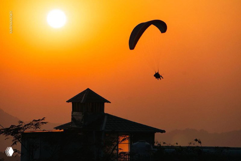 Параплан и тандемный пилот на фоне оранжевого заката над зданием — тёплый и атмосферный снимок из галереи побед.