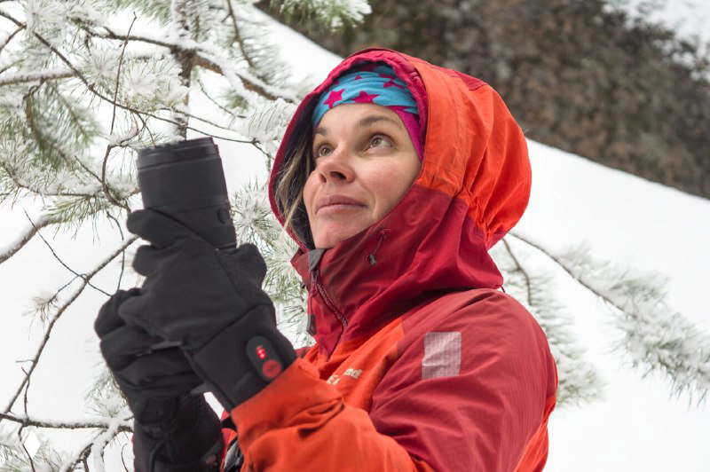Портрет пилота‑инструктора и фотографа в ярко‑красной куртке с камерой на снежном фоне — авторская фотография с выразительным взглядом.