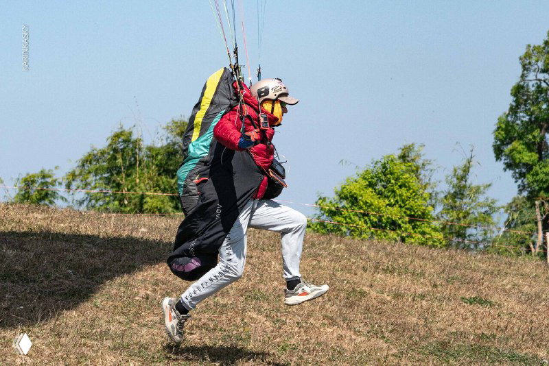 Старт тандемного полёта: инструктор и пассажир бегут по склону с парапланом, подготовка к взлёту в поле — динамичный момент выезда.